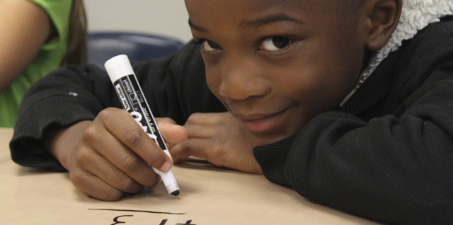 Smiling boy with marker writing letters on a pad